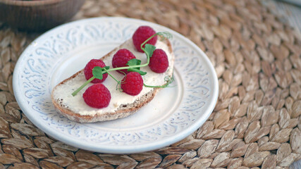 Sweet bruschetta with cream cheese and fresh berries. Homemade healthy breakfast with bread, cheese, blueberries and raspberries. Three delicious sandwiches on a plate