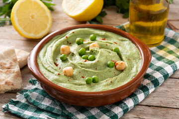 Green pea hummus and pita bread on wooden table