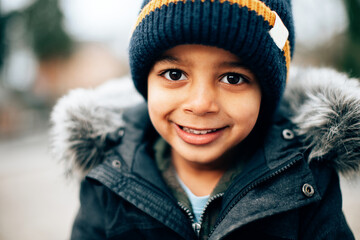 close up portrait of mixed race cute happy smiling child on a cold winter day