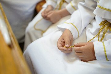 children in festive attire sit on benches in the church during Holy Communion
