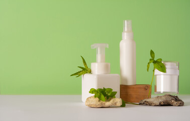 A set of cosmetics products with natural materials on a green background. Stones, plant and wooden decorative figures. Natural organic cosmetic. Beauty concept. Wabi sabi trend