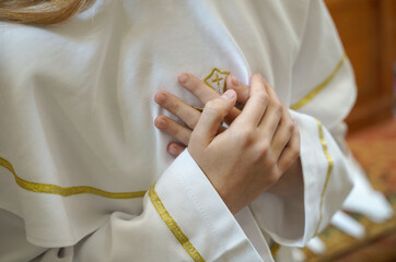 folded hands of a child on the heart before receiving Holy Communion