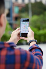 Over shoulder view of man in wristwatch using online app while navigating to place in city