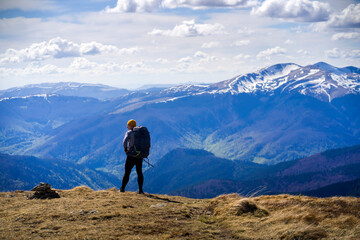 The traveler looks at the stunning view of the snow-capped mountains at sunset. Young man with a...
