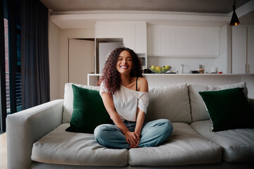 Mixed race African American female sitting on couch smiling while relaxing at home