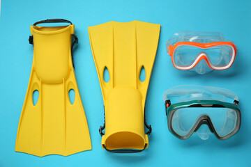 Pair of yellow flippers and masks on light blue background, flat lay © New Africa