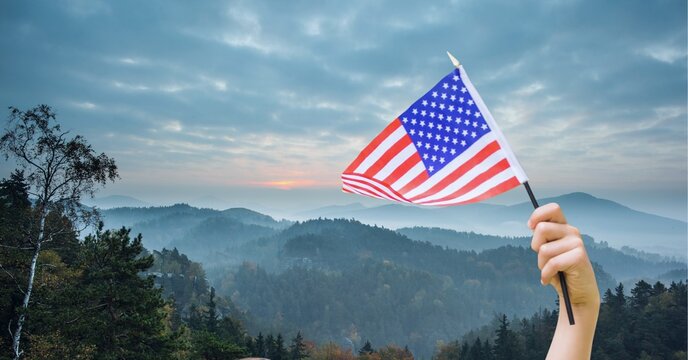 Composition of caucasian hand holding american flag over landscape