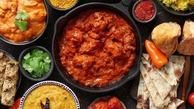 Various Indian dishes on a table. Spicy chicken Tikka Masala in iron pan