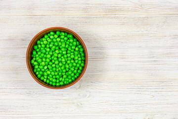 Obraz na płótnie Canvas Fresh green peas in a bowl on a white background. View from above. Place for an inscription.