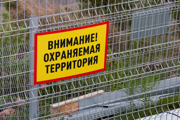 A warning sign on the fence with the inscription in Russian, 