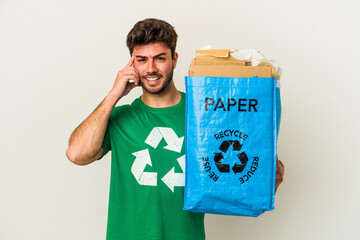 Young caucasian man man recycling cardboard isolated on white background showing a disappointment gesture with forefinger.