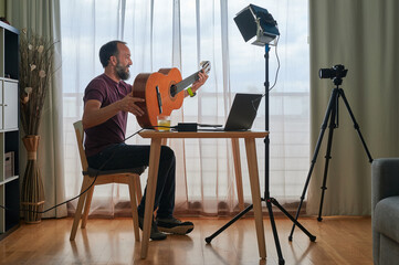 middle-aged man recording a video about music in his home studio with natural and artificial lighting