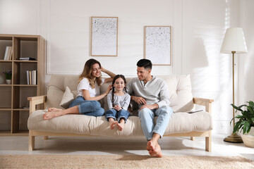 Happy family with little daughter sitting on sofa in living room