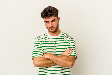 Obraz premium Young caucasian man isolated on white background frowning face in displeasure, keeps arms folded.