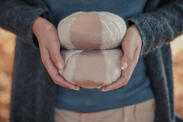 Person hands hold soft colored alpaca yarn with blank labels. Female hobby and leisure knitting...