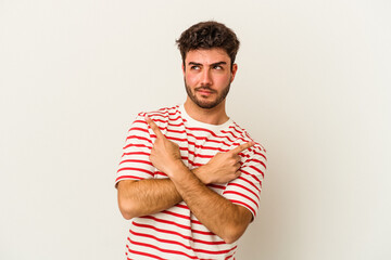 Young caucasian man isolated on white background points sideways, is trying to choose between two options.