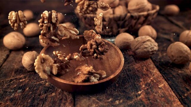 Super slow motion plate with walnuts falls on the table. On a wooden background.Filmed on a high-speed camera at 1000 fps. High quality FullHD footage