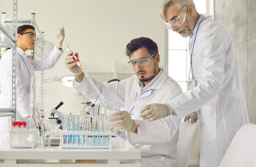 Group of serious scientists working in laboratory, doing advanced scientific research, making...