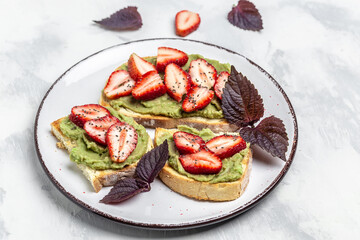 toast with shaped avocado,fresh strawberries and chia seeds on plate. vegan healthy food concept. Top view