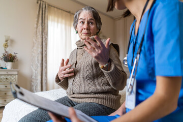 A young nurse takes care of an elderly 80-year-old woman at home, explains the methods of...