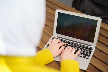 Back view of a muslim woman in hijab using laptop in cafe