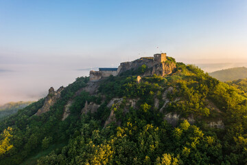 Fototapeta na wymiar Aerial view abour castle of Sirok with misty matra mountains at the background. Spring sunrise landscape.
