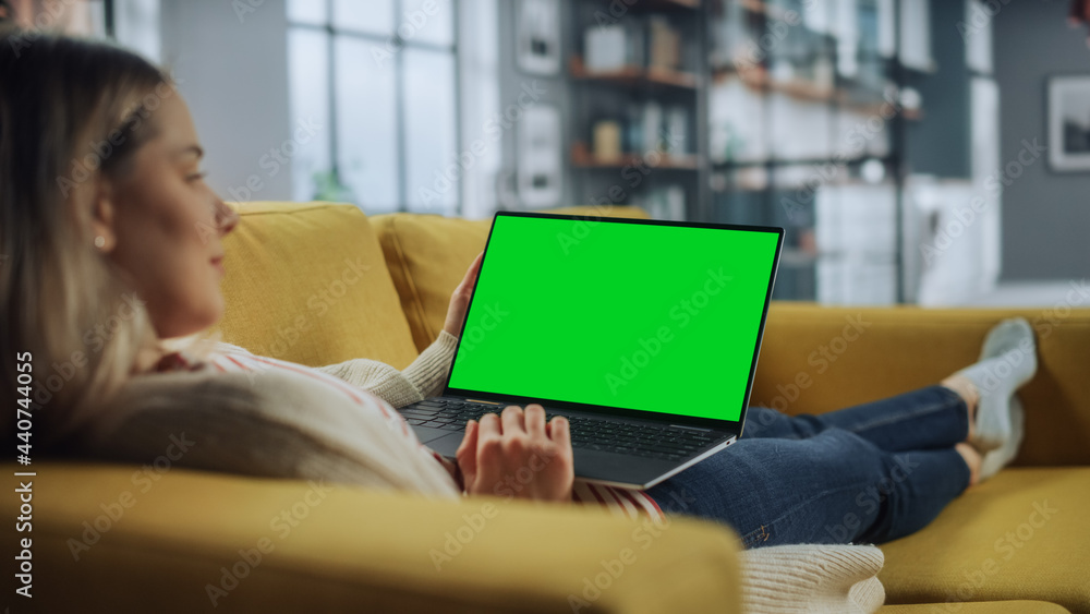 Poster beautiful caucasian specialist working on laptop with green screen mock up display at home living ro
