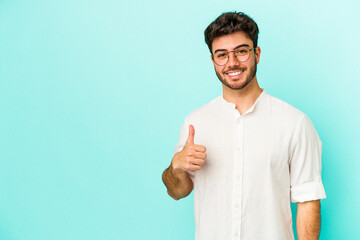 Young caucasian man isolated on blue background smiling and raising thumb up