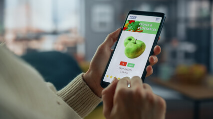 Close Up on Hands Using Online Food Shopping App on a Horizontally Held Smartphone at Home Living...