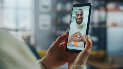 Close Up of a Female Chatting in a Video Call with Her Handsome Male African American Friend on Smartphone from Home Living Room. Freelancer Making a Call with Manager Over the Internet. - obrazy, fototapety, plakaty
