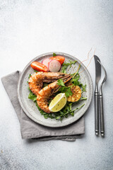 grilled tiger prawns with vegetables on a ceramic plate, top view