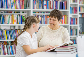 Happy teacher and girl with syndrome down read a book at library. Education for disabled children...