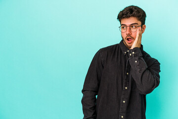 Young caucasian man isolated on blue background being shocked because of something she has seen.
