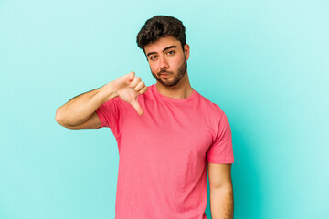 Young caucasian man isolated on blue background showing thumb down, disappointment concept.