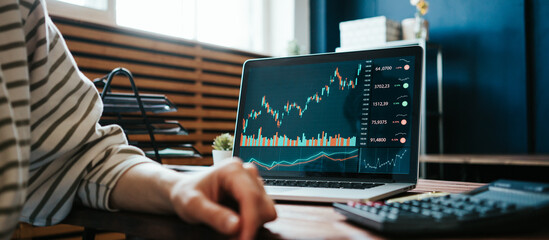 Woman investing in world stock market, using her laptop and online trading soft from home