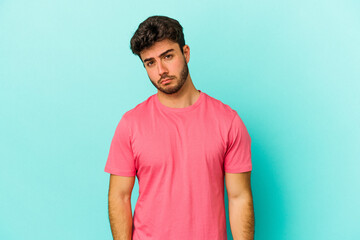 Young caucasian man isolated on blue background sad, serious face, feeling miserable and displeased.
