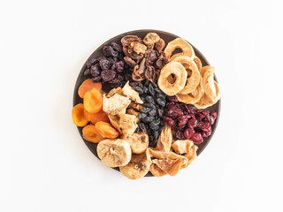 Dried or sun-dried berries and fruits on plate on white background.