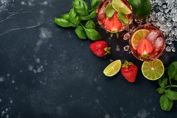 Two glasses of punch and fresh ingredients for making lemonade, infused detox water or cocktail. Strawberries, lime, mint, basil, ice cubes and shaker on black stone or concrete background. Top view.