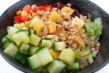 Vegetarian poke bowl in design black bowl with chopsticks below, isolated on white background. Green cucumber, red pepper, peanuts, corn, beetroot on top of sushi rice. Healthy vegetarian food.