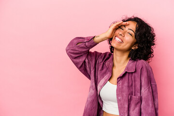 Young curly latin woman isolated on pink background laughing happy, carefree, natural emotion.