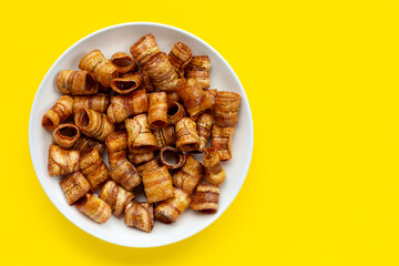 Dried banana rolled chips on yellow background.