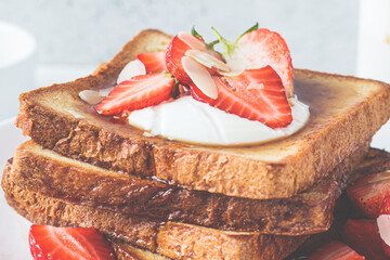 A stack of French toast with strawberries, yogurt and maple syrup. Breakfast concept.