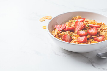 Cornflakes with strawberries in white bowl. Healthy breakfast concept.