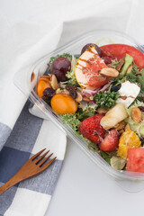 Fruit and vegetable salad in a package on white table.