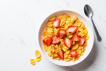 Cornflakes with strawberries in white bowl. Healthy breakfast concept.