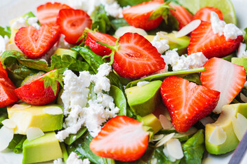 Close-up of strawberry salad with spinach, feta cheese, avocado and almonds.