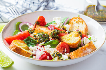 Italian salad with tomatoes, feta cheese and grilled ciabatta, marble background.