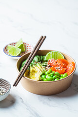 Poke bowl with rice, salmon, edamame beans, cucumber and avocado in reusable cardboard bowl. Hawaiian food. Zero Waste concept.