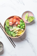 Poke bowl with rice, salmon, edamame beans, cucumber and avocado in reusable cardboard bowl. Hawaiian food. Zero Waste concept.