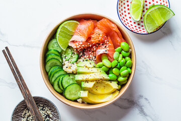 Poke bowl with rice, salmon, edamame beans, cucumber and avocado in reusable cardboard bowl....